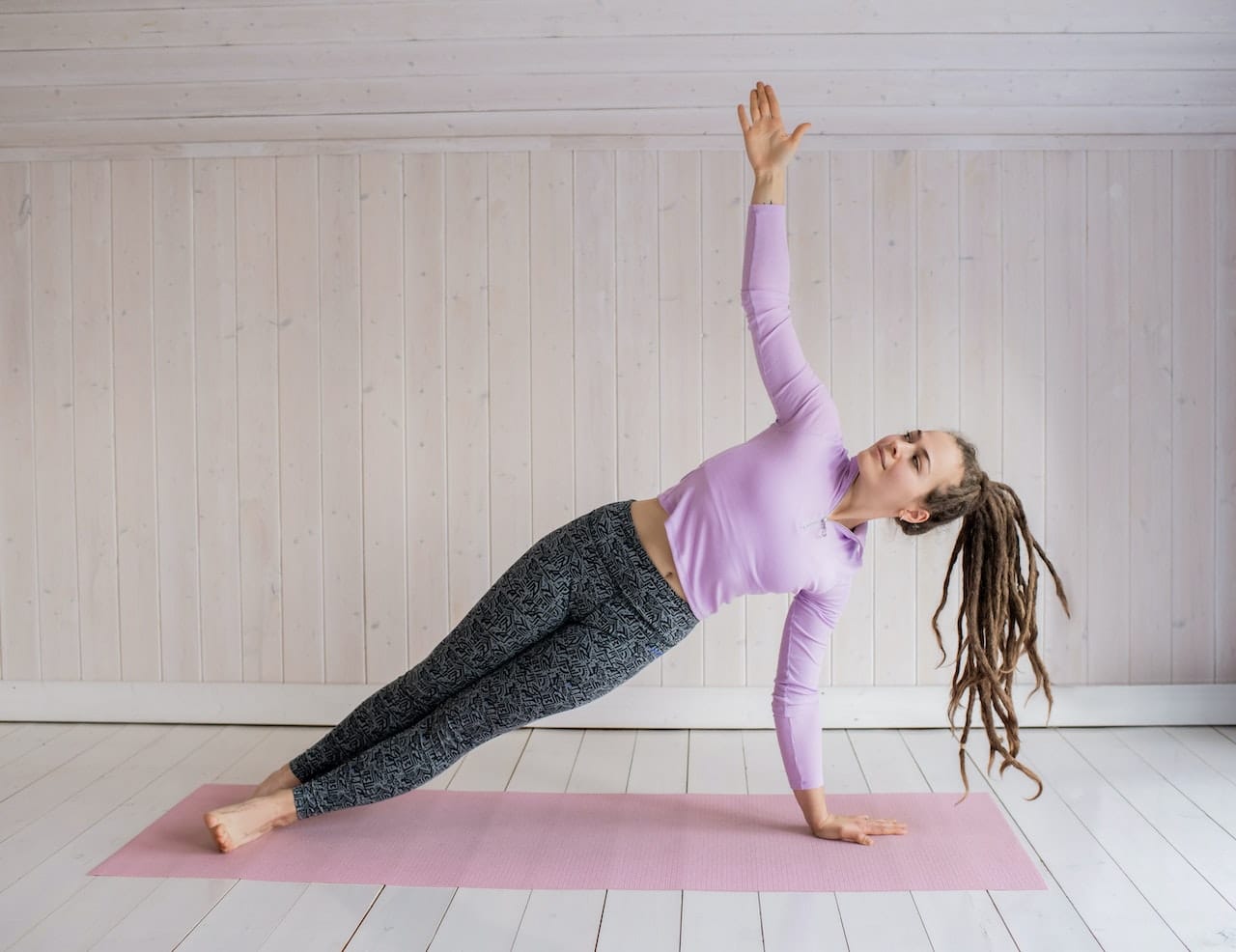 Frau in Side-plank auf pinker Yogamatte